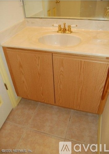 A bathroom with a sink and wooden cabinets.
