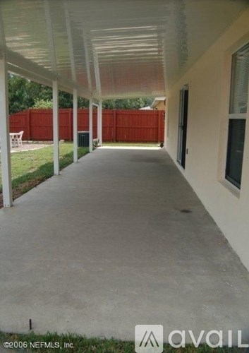 A long covered walkway with a white ceiling and a red fence in the background.