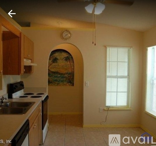A kitchen with a painting of a beach scene on the wall.