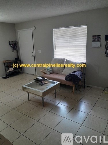 A living room with a glass coffee table and a person sitting on a chair.