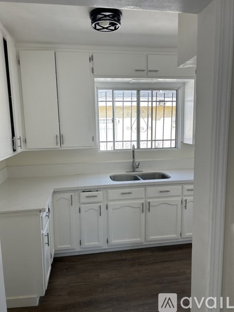 A kitchen with white cabinets and a window.