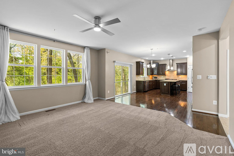 A spacious living room with a ceiling fan and large windows.