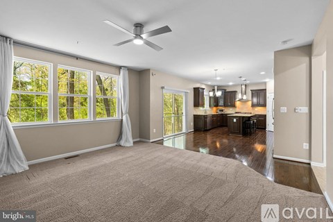 A spacious living room with a ceiling fan and large windows.