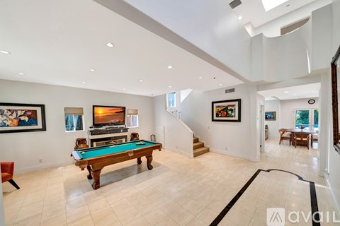 A pool table is in the middle of a room with a white ceiling and walls.