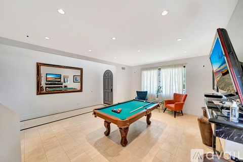 A room with a pool table and a television.