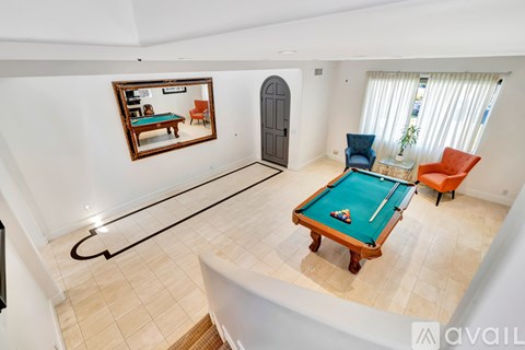 A room with a pool table and a mirror on the wall.