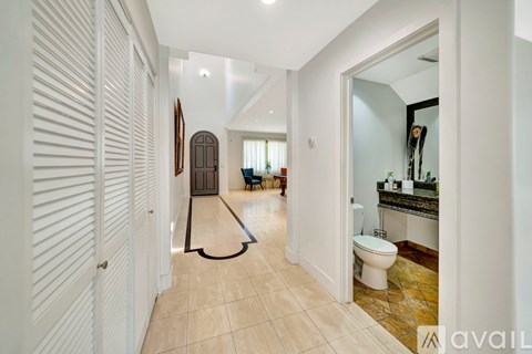 A hallway with a toilet and sink visible through the door.