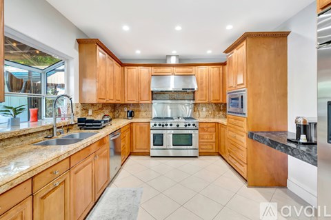 A kitchen with wooden cabinets and a marble countertop.