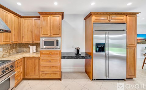 A kitchen with wooden cabinets and a stainless steel refrigerator.