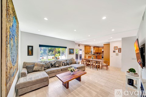 A living room with a couch, a coffee table, and a painting on the wall.