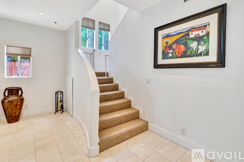 A painting hangs on the wall above a staircase in a home.