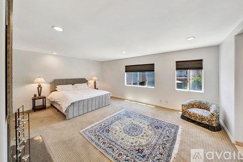 A bedroom with a large bed, a bench, and a rug.