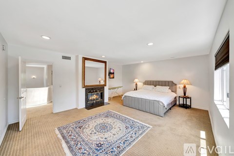 A bedroom with a large bed and a fireplace.