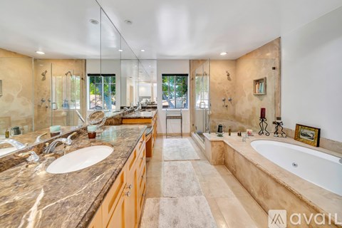 A bathroom with a marble countertop and a large tub.