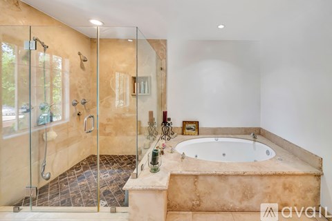 A bathroom with a glass shower stall and a jacuzzi tub.
