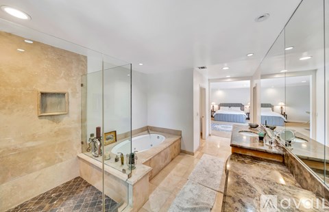 A bathroom with a glass shower enclosure and a large tub.