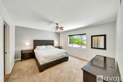 A bedroom with a large bed and a ceiling fan.