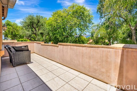 A balcony with a chair and a wall.