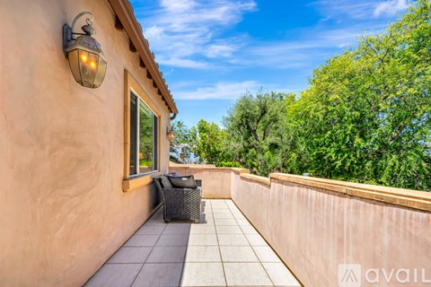 A balcony with a table and chairs overlooking a garden.