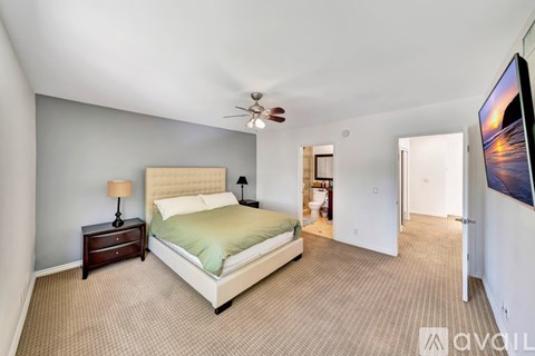 A bedroom with a large bed and a ceiling fan.