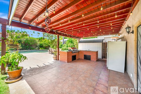 A patio with a red roof and a white refrigerator.