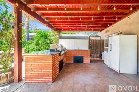A patio with a brick fireplace and a red pergola.