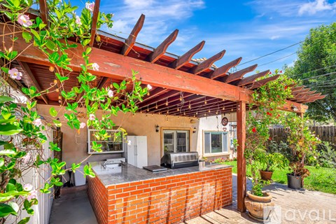 A patio with a brick wall and a wooden pergola.