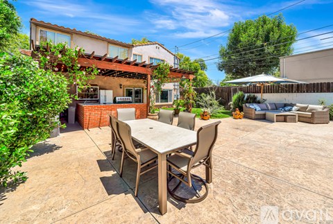 A patio with a table and chairs is surrounded by greenery.