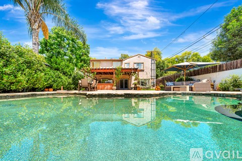 A house with a pool in the foreground and a palm tree in the background.
