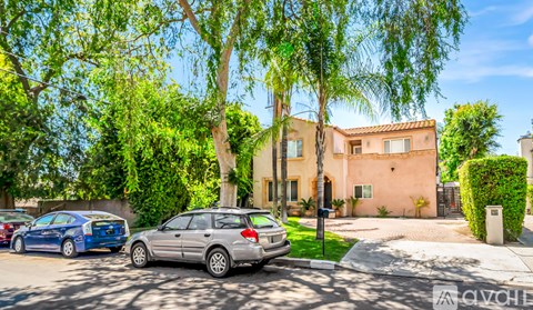 A silver car is parked in front of a house with a blue car parked behind it.