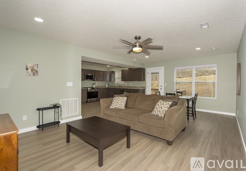 A living room with a brown couch and a ceiling fan.