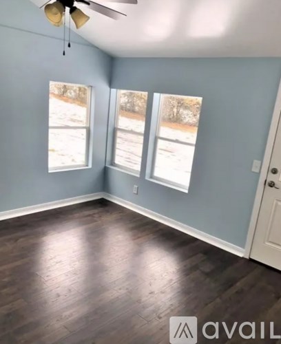 A room with a ceiling fan and two windows.