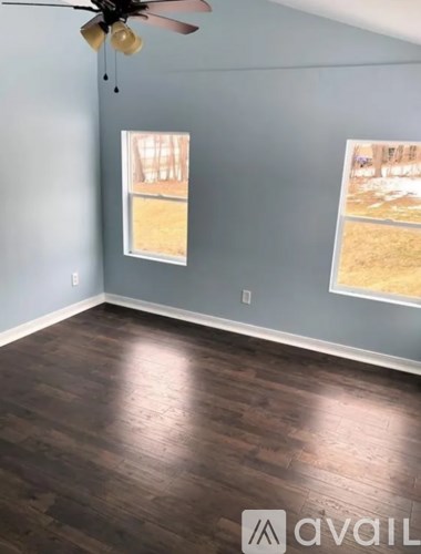 A room with a ceiling fan and two windows.