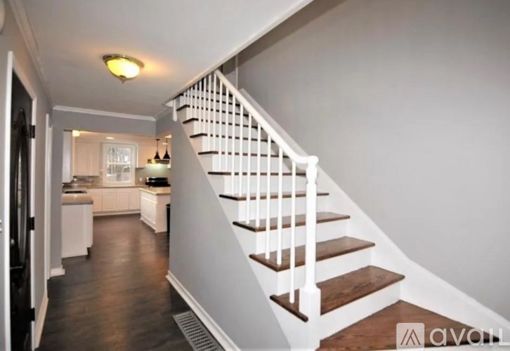 A staircase with white railings leads to a kitchen area.