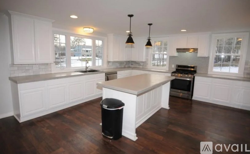 A kitchen with white cabinets and a wooden floor.