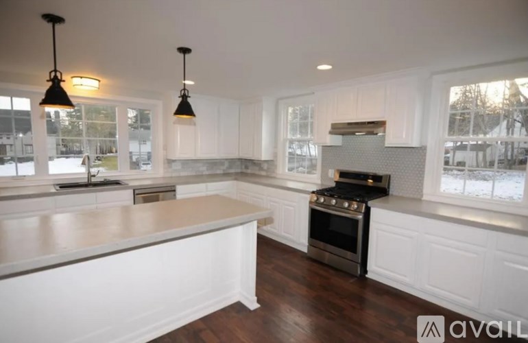 A modern kitchen with white cabinets and a dark wood floor.