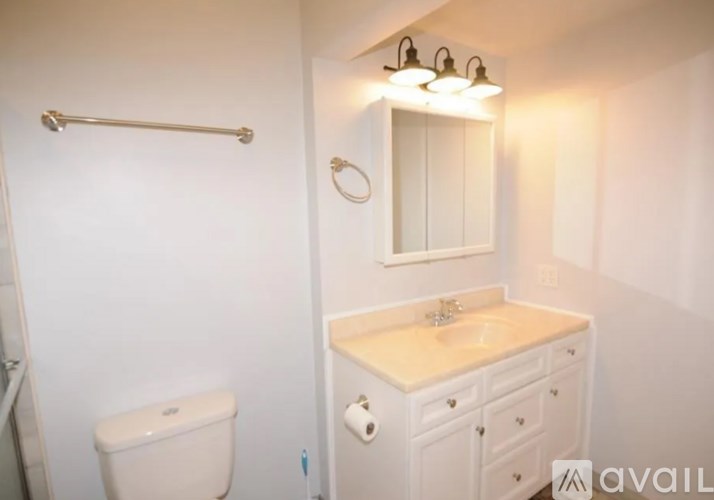 A white bathroom with a toilet, sink, and mirror.