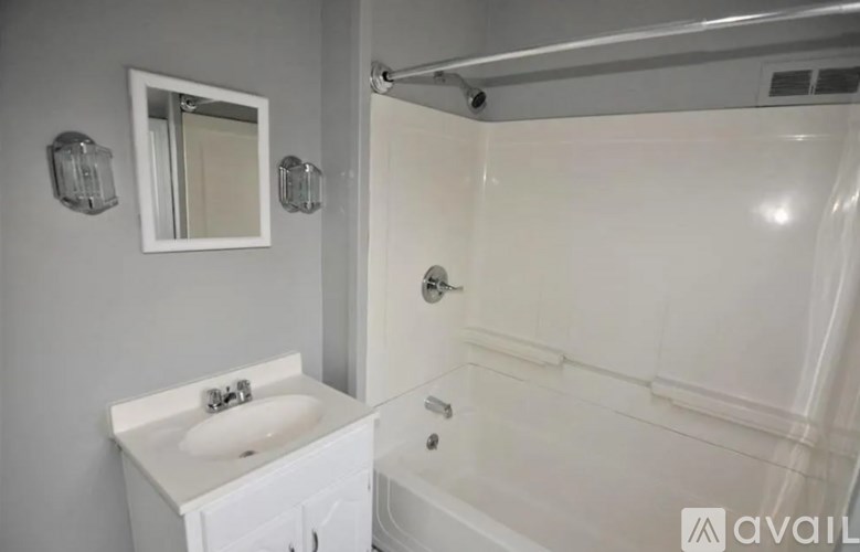 A white bathroom with a sink, mirror, and bathtub.