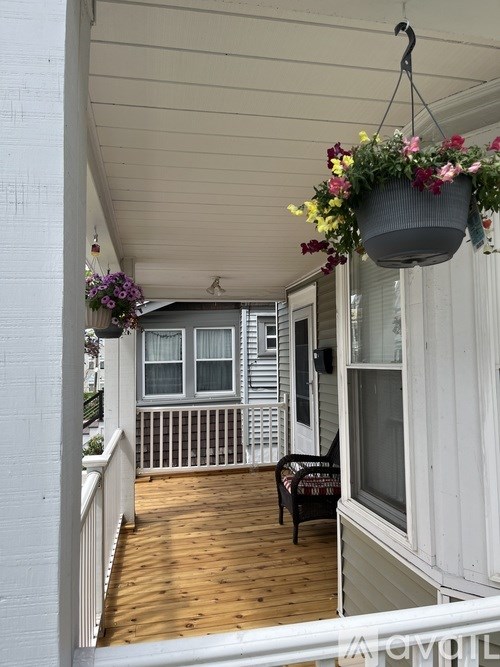 A balcony with a bench and hanging flower pots.