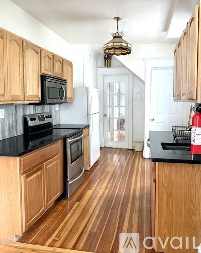 A kitchen with wooden cabinets and black countertops.