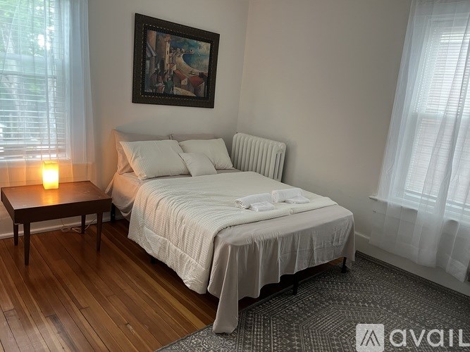 A bedroom with a bed, nightstand, and a painting on the wall.