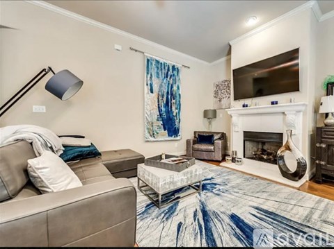 A living room with a grey couch, a coffee table, a fireplace, and a painting on the wall.