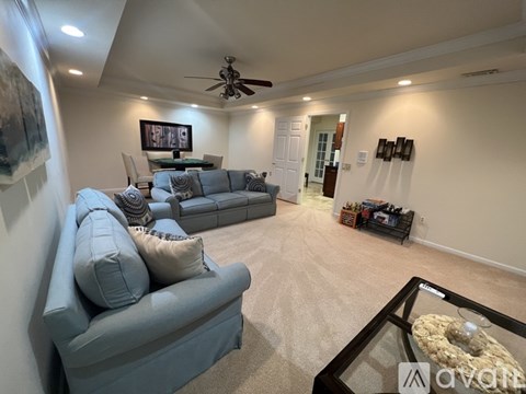 A living room with a grey couch and a glass coffee table.