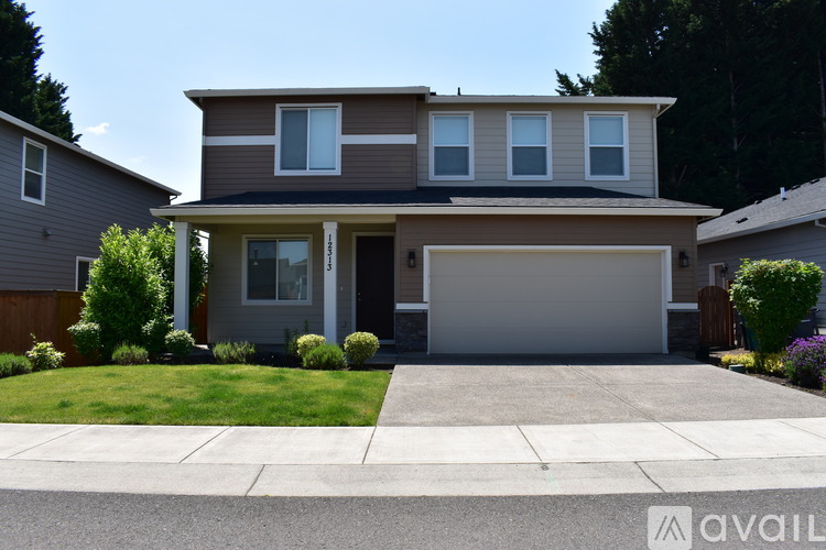 A modern house with a grey garage door and a brown roof.