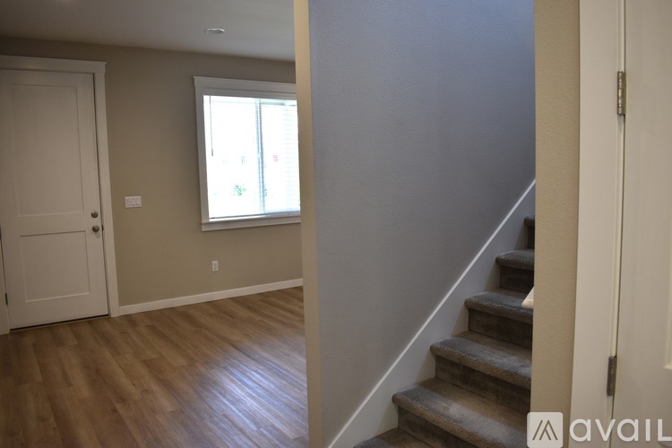 A room with wooden floors and a staircase leading to another room.