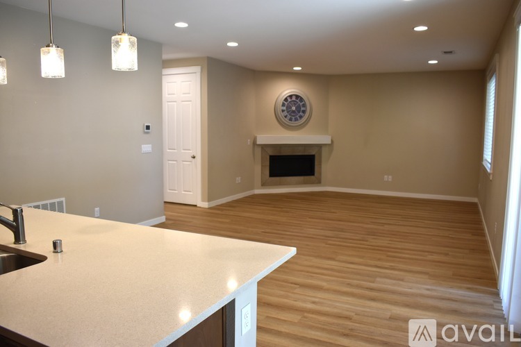 A kitchen with a white countertop and a fireplace in the living room.