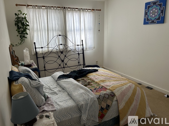 A bedroom with a bed, a lamp, and a painting on the wall.