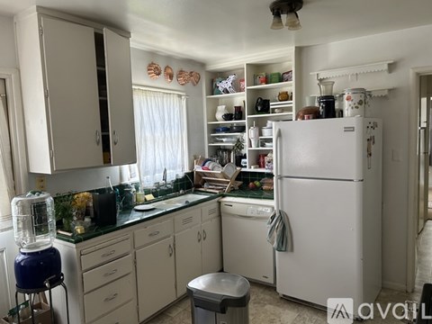 A kitchen with a white refrigerator and cabinets.