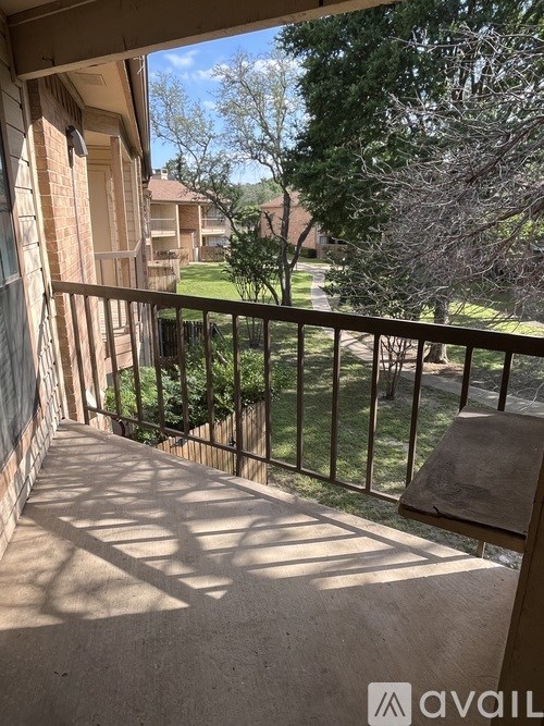 A balcony with a view of a green lawn and houses.