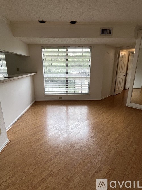 A room with wooden flooring and a window with blinds.